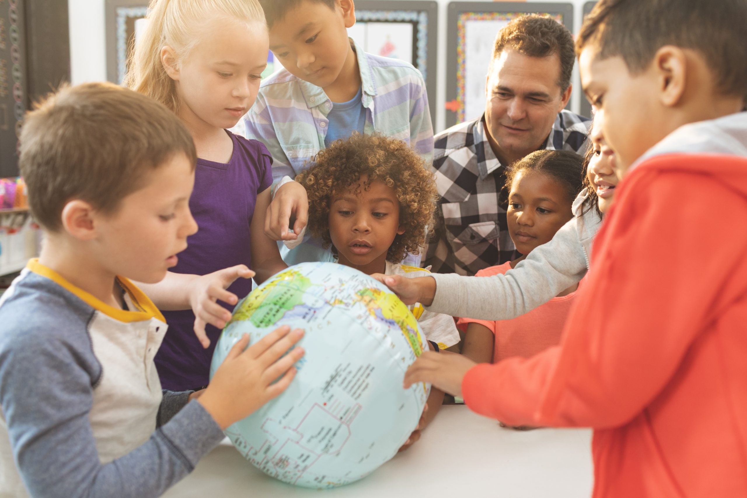 Schoolteacher discusing over a earth globe in classroom at schoo